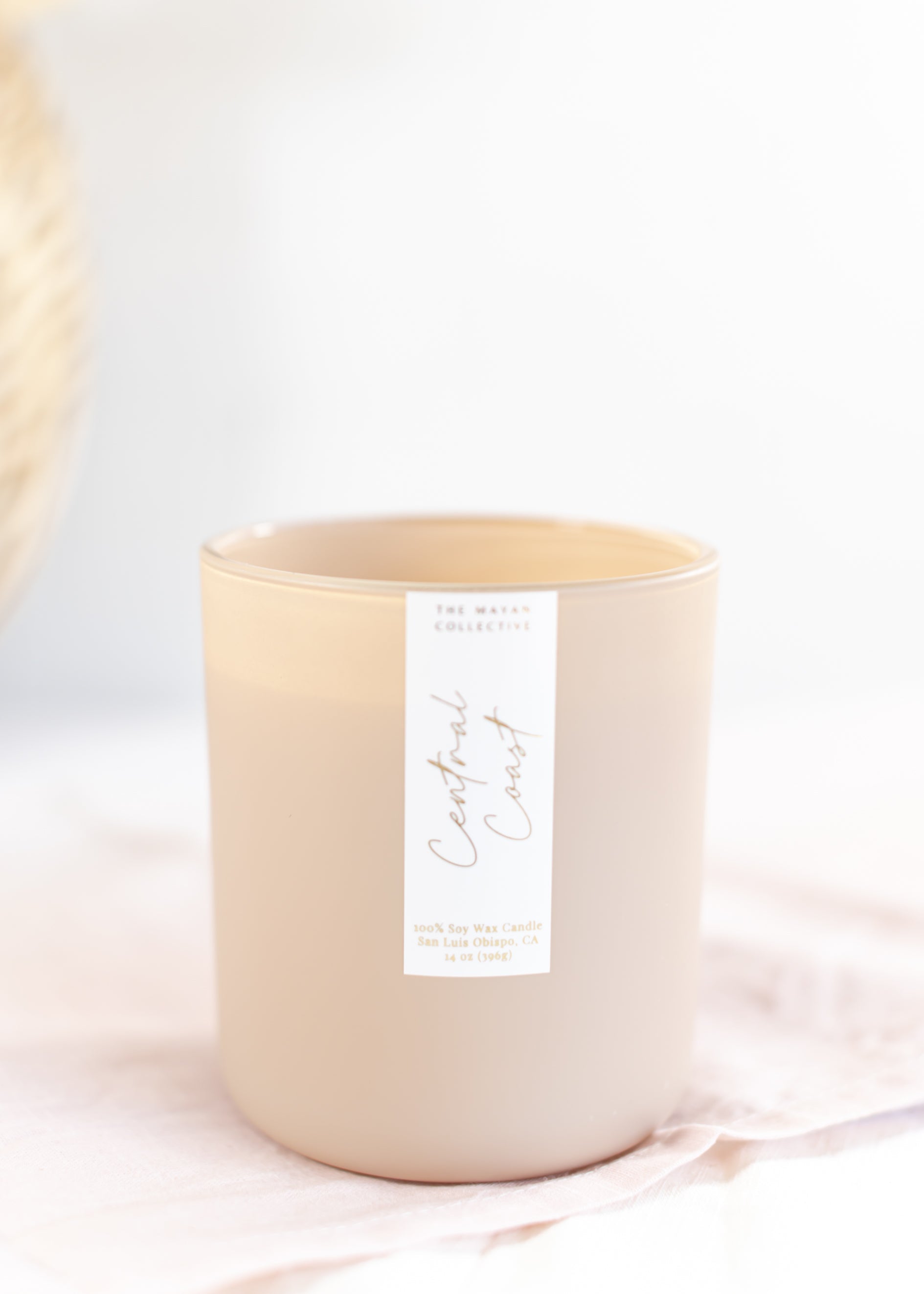 Beige candle with a white label on a light pink background