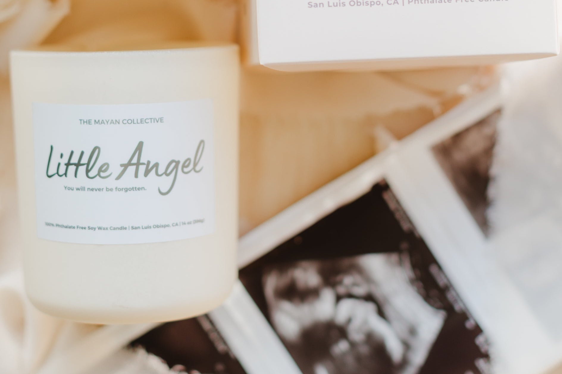 Candle labeled 'Little Angel' with ultrasound photo and card in the background