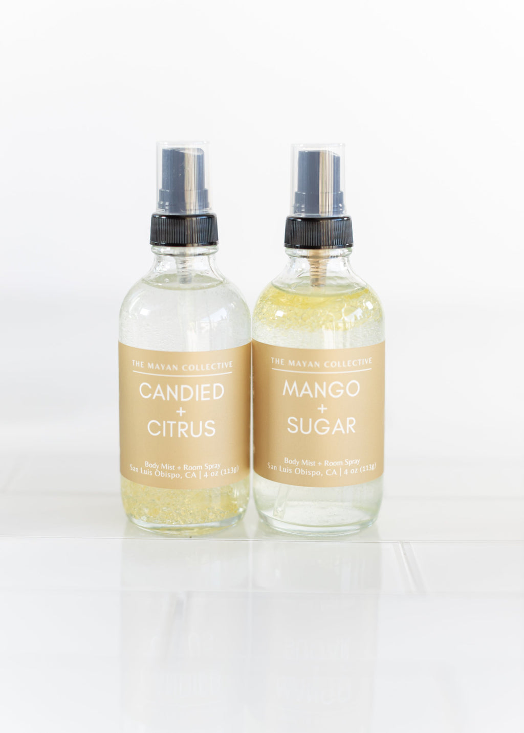 Two glass spray bottles labeled 'Candied Citrus' and 'Mango Sugar' on a white background.