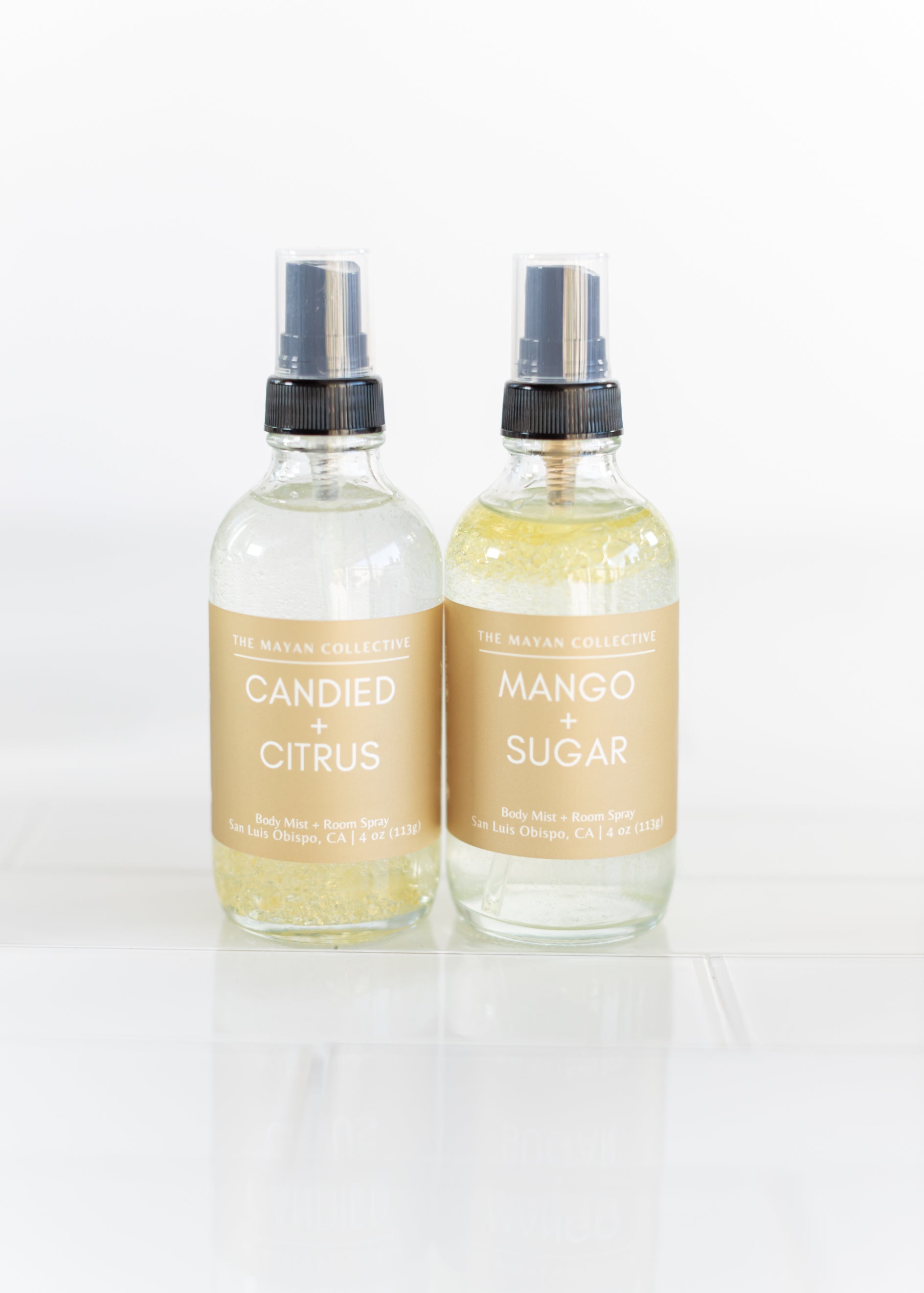 Two glass spray bottles labeled 'Candied Citrus' and 'Mango Sugar' on a white background.
